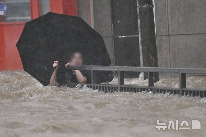 [광주=뉴시스] 이영주 기자 = 광주지역에 하루 최고 311㎜ 폭우가 쏟아진 17일 오후 침수된 광주 북구청 앞 도로에서 한 시민이 물살에 휩쓸리고 있다. 시민은 자력으로 무사히 대피했다. 2025.07.17. leeyj2578@newsis.com