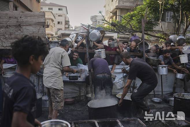 [가자시티=AP/뉴시스]지난 14일(현지 시간) 가자지구 가자시티 내 한 공동 급식소에서 팔레스타인 주민들이 음식을 받기 위해 몰려들고 있다. 2025.07.18.