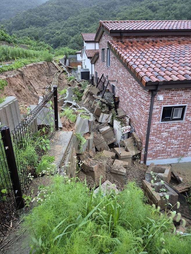 LPG통 위로 무너진 옹벽 - 17일 충북 음성군 음성읍의 한 주택 뒷마당에 200㎏ 용량 LPG 용기가 폭우로 무너진 옹벽에 묻혀 있는 모습. 가스가 소량 누출됐으나 긴급 안전조치로 추가 피해는 발생하지 않았다. 음성 연합뉴스