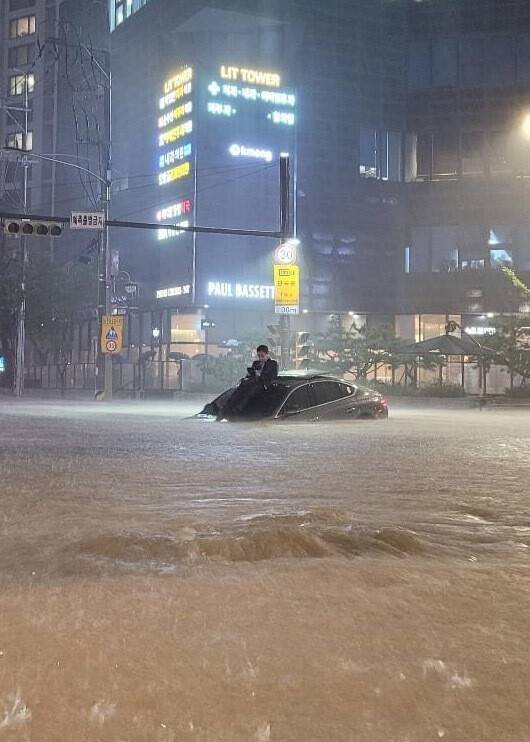 2022년 8월8일 밤 서울 강남구 대치역 인근에서 물에 잠긴 자동차 위로 시민이 올라가 대피해 있다. 당시 윤석열 대통령은 서울 서초동 집으로 퇴근했다. 에스엔에스 갈무리