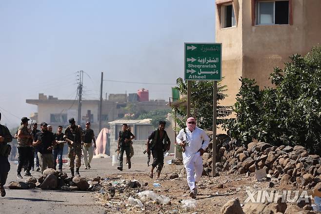18일(현지시간) 베두인족 전투원들이 시리아 남부 스웨이다 지역 한 마을을 통과하고 있다.  [신화=연합뉴스]