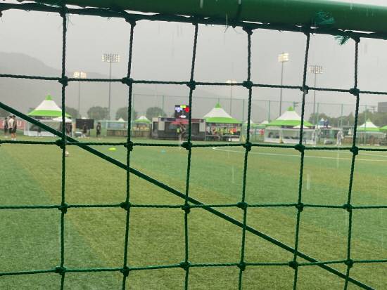 지난 18일 합천군민체육공원 인조잔디구장에서 '2025 추계 전국고등축구대회' 개막전을 앞두고 폭우가 쏟아지는 가운데, 선수들과 대회 관계자들이 빗속에서 대기하고 있다.