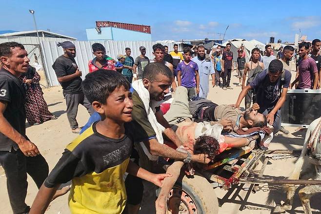 2025년 7월12일 팔레스타인 땅 가자지구 남부 칸유니스의 ‘가자인도주의기금’(GHF) 식량배급소 주변에서 주민들이 이스라엘군의 총격으로 목숨을 잃은 사람들을 수레에 실어 옮기고 있다. AFP 연합뉴스