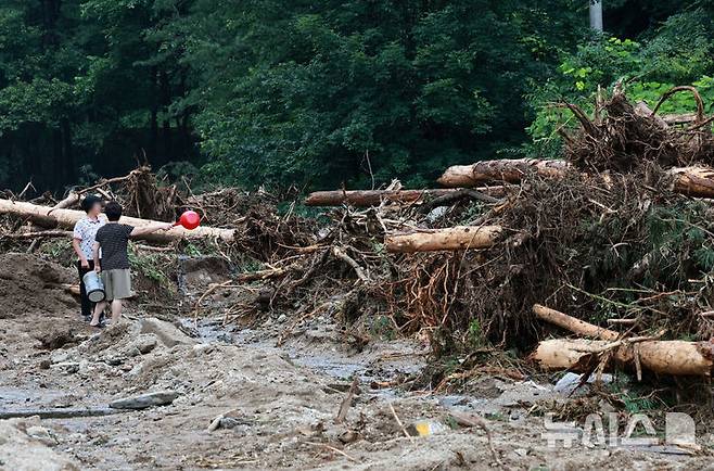[가평=뉴시스] 이영환 기자 = 20일 오후 경기 가평군 조종면 십이탄천 인근에서 주민들이 폭우에 떠내려온 나무르 바라보고 있다. 2025.07.20. 20hwan@newsis.com