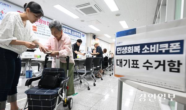 민생회복 소비쿠폰 1차 신청 첫날인 21일 오전 화성시 병점 1동 행정복지센터에서 한 어르신이 소비쿠폰을 발급받은 후 사용방법을 설명 듣고 있다. 2025.7.21 /임열수기자 pplys@kyeongin.com