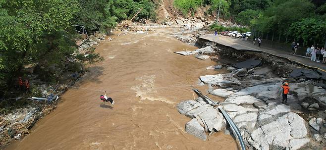 20일 경기 가평군 마일리 한 캠핑장에 놀러온 시민들이 집중호우로 길이 끊어지자 줄을 타고 하천을 건너 탈출하고 있다. 연합뉴스.