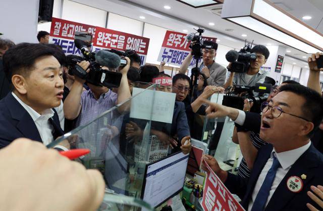 전북 전주·완주 행정 통합을 추진 중인 김관영 전북도지사(왼쪽)가 21일 완주군 삼례읍 행정복지센터에서 전입신고를 하자 유의식 완주군의장이 항의하고 있다. 연합뉴스