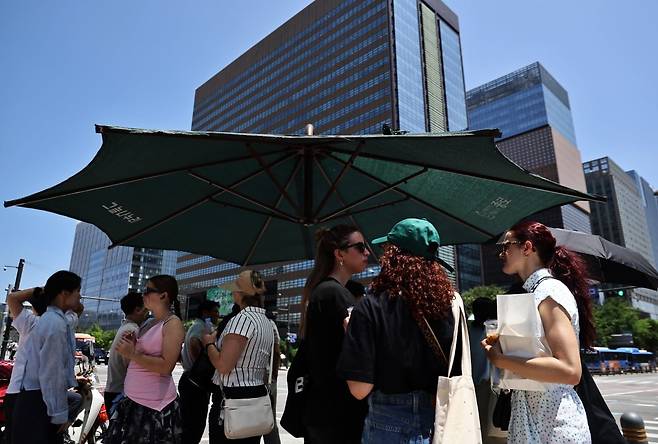무더위가 이어졌던 지난 10일 서울 세종로 사거리에서 시민들이 햇빛 가림막 아래에서 신호를 기다리고 있다. 연합뉴스