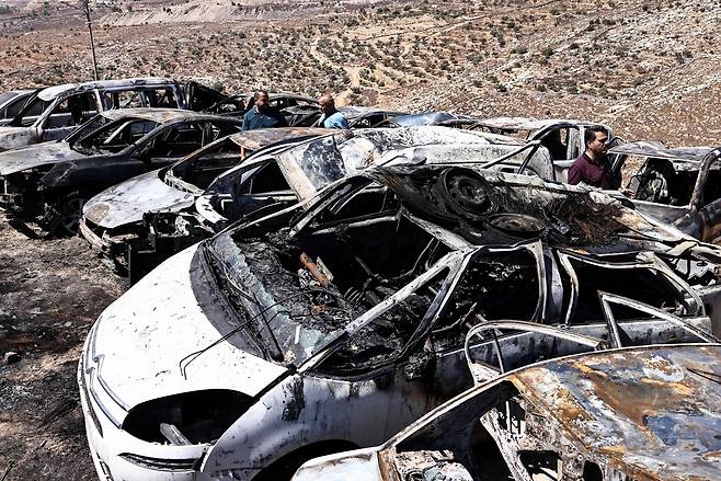 15일 (현지시간) 이스라엘이 점령한 서안지구 라말라 동쪽 부르카 마을에서 이스라엘 정착민들이 심야에 공격을 감행한 것으로 알려진 가운데, 주민들이 불에 타 파괴된 차량을 살펴보고 있다. AFP연합뉴스