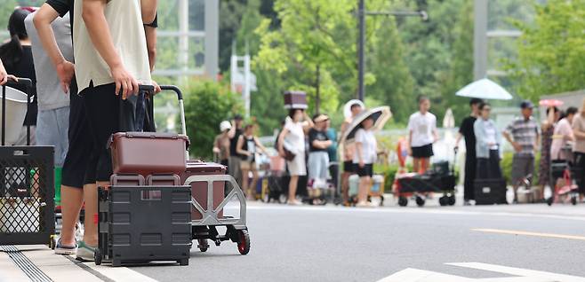 Residents of an apartment complex in Eonyang-eup, Ulju County, Ulsan, line up with containers and carts to collect water from a tanker truck on July 21, the second day of a water outage. [YONHAP]