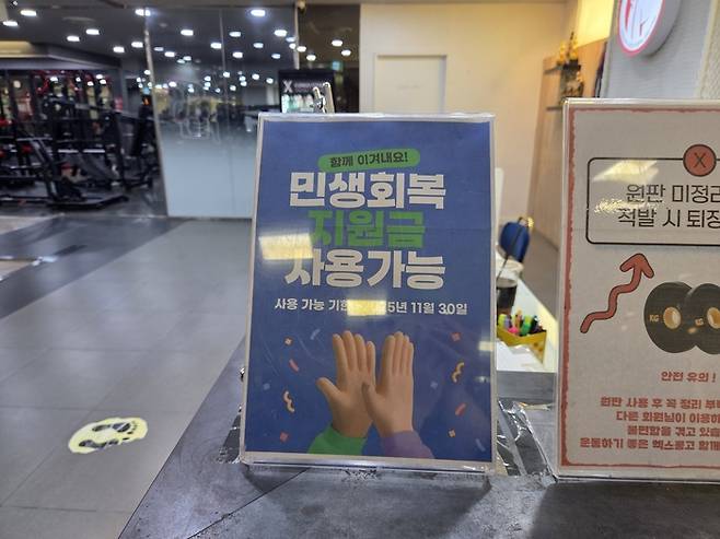 서울 동작구에 위치한 한 헬스장에 민생회복 소비쿠폰 사용이 가능하다는 안내판이 놓여있다. [권민선 인턴기자]
