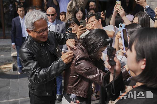 [베이징=AP/뉴시스] 젠슨 황 엔비디아 최고경영자(CEO)가 16일(현지 시간) 중국 베이징에서 열린 제3회 중국 국제 공급망 촉진 박람회(CISCE) 참석 후 만다린 오리엔탈 첸먼 호텔에서 기자회견하면서 한 기자의 가죽 재킷에 사인을 해주고 있다. 2025.07.16.