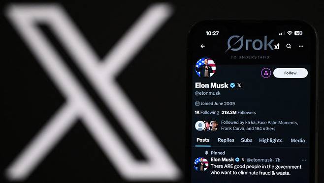 노트북 화면에 표시된 X 로고 옆으로, 일론 머스크의 X 계정이 휴대전화 화면에 표시돼 있다(사진=AFP)