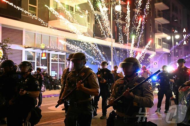 2025년 6월 9일 로스앤젤레스(LA) 시내 리틀 도쿄 인근에서 연방 이민단속 작전에 대응하는 시위 도중 진압 장비를 착용한 벤투라 카운티 보안관 사무실 소속 대원들 뒤로 폭죽이 터지고 있다. ⓒ AFP=뉴스1 ⓒ News1 신기림 기자