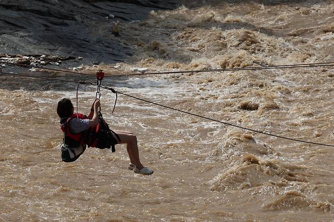20일 경기 가평군 마일리의 한 캠핑장에 고립된 시민들이 소방 로프를 타고 탈출하고 있다./뉴스1