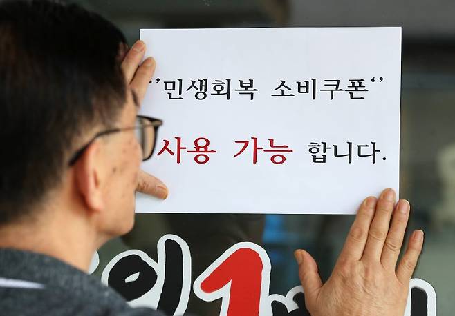 22일 대구 중구의 한 음식점 주인이 출입문에 민생회복 소비쿠폰 사용 가능 안내문을 붙이고 있다. 뉴스1