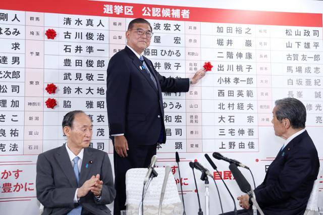 이시바 시게루(가운데) 일본 총리 겸 집권 자민당 총재가 참의원 선거가 실시된 20일 도쿄 당사 개표 본부에서 당선된 후보 이름에 꽃을 달고 있다. 도쿄=지지·AFP 연합뉴스