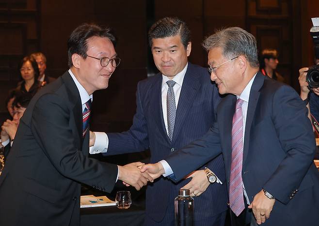 Prime Minister Kim Min-seok, left, shakes hands with acting U.S. Ambassador Joseph Yun, right, at a seminar hosted by the American Chamber of Commerce (Amcham) in Korea at the Conrad Hotel in Yeouido, western Seoul, on July 22. Amcham chair and CEO James Kim stands in the middle. [YONHAP]