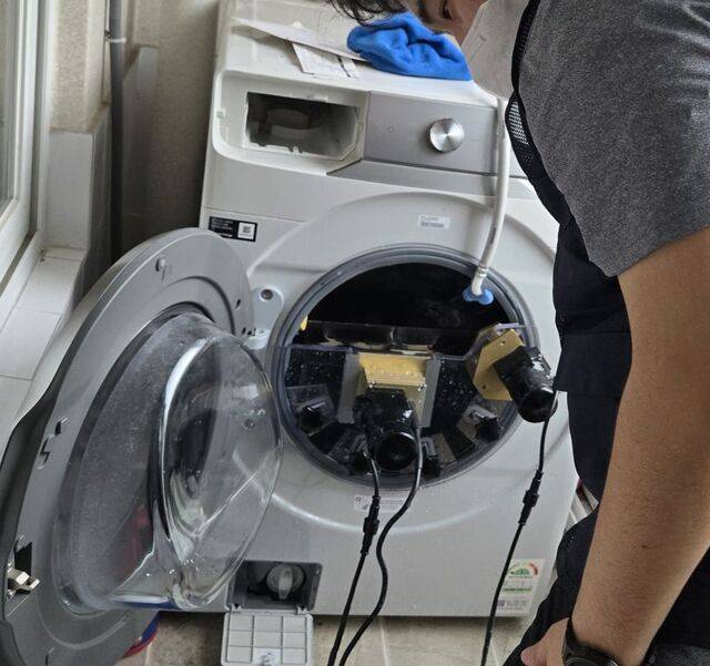 삼성전자서비스 엔지니어가 지난 17일 드럼 세탁기에 초음파 기기를 연결해 통 내부를 세척하고 있다.