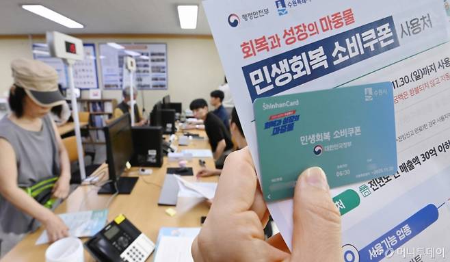 정부의 민생회복 소비쿠폰 1차 신청 첫날인 21일 경기 수원시 행궁동 행정복지센터에서 한 시민이 선불카드를 수령받고 있다.   소비쿠폰 신청은 요일제에 따라 출생 연도 끝자리 1·6은 월요일, 2·7은 화요일, 3·8은 수요일, 4·9는 목요일, 5·0은 금요일에 신청할 수 있다.   주말에는 온라인 신청만 가능하며 사용기한은 11월 30일까지다. /사진제공=뉴시스