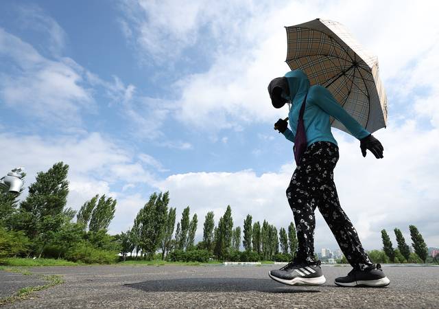21일 서울 영등포구 여의도한강공원에서 한 시민이 우산을 쓰고 이동하고 있다. 연합뉴스