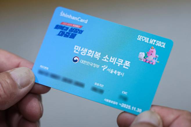 민생회복 소비쿠폰 신청 첫날인 21일 오전 서울 종로구 주민센터에서 시민이 민생회복 소비쿠폰을 받은 뒤 들어보이고 있다. 뉴시스