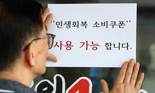 22일 대구 중구의 한 음식점 주인이 출입문에 민생회복 소비쿠폰 사용 가능 안내문을 붙이고 있다. 뉴스1