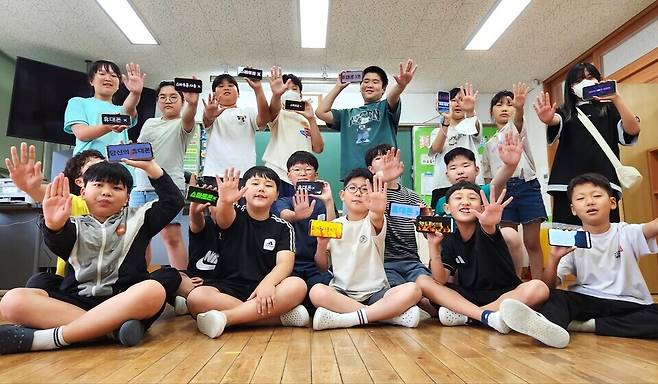 ▲ 양주 덕도초등학교 학생들이 스마트폰 화면에 '휴대폰 X', '소통 불가', '스마트폰 사용 X' 등의 문구를 띄운 뒤 스마트폰 사용을 줄이자는 의미로 손바닥을 펼쳐 보이고 있다.