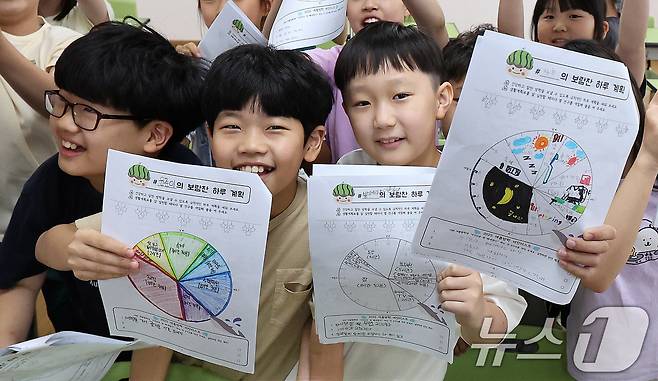 23일 서울 동작구 삼일초등학교에서 열린 여름 방학식에서 학생들이 여름방학 계획표를 들어보이며 기뻐하고 있다. 2025.7.23/뉴스1 ⓒ News1 박지혜 기자