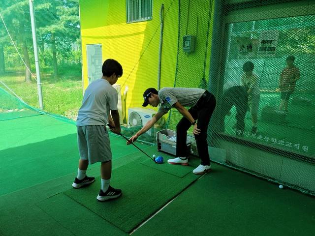 박준홍 선수가 ‘드림라운드’에 참석한 학생에게 어드레스를 알려주고 있다. [우리금융그룹 제공]