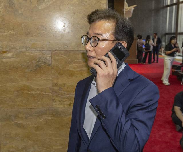 전재수 해양수산수 장관 후보자가 23일 국회 본회의에 앞서 열린 더불어민주당 의원총회에 전화를 받으며 입장하고 있다. [연합뉴스]