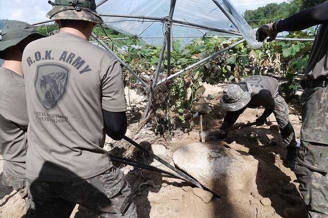 23일 경기도 가평군 상면 수해 지역에서 육군 수도기계화보병사단 혜산진여단 장병이 중장비 진입이 불가능한 포도밭을 덮친 바윗돌을 치우고 있다. 연합뉴스
