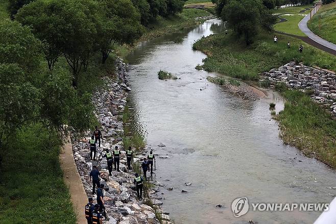 지난 21일 불어난 물에 휩쓸린 실종자 수색작업 중인 경찰. 연합뉴스