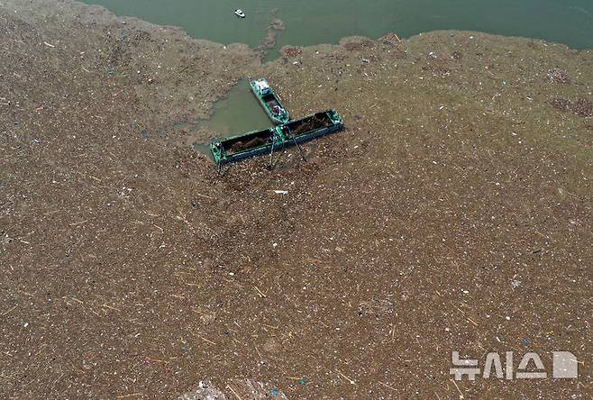 [남양주=뉴시스] 이영환 기자 = 23일 오전 경기도 남양주시 팔당댐 수면에서 관계자들이 호우로 떠내려온 쓰레기와 부유물 처리 작업을 하고 있다.  2025.07.23. 20hwan@newsis.com