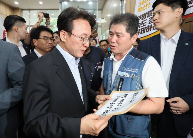 22일 서울 중구 민주노총을 찾은 김민석 국무총리가 위원장실로 향하던 중 민주노총 조합원들로부터 현안을 담은 요구안을 전달받고 있다. 연합뉴스