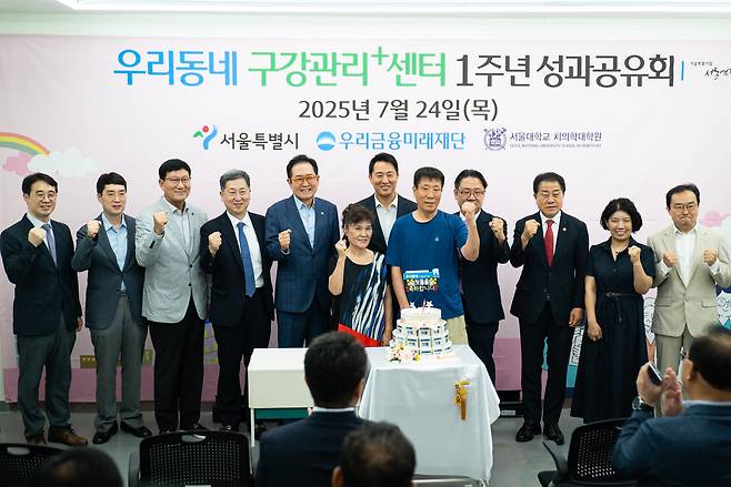 24일 우리동네 구강관리플러스센터에서 오세훈 서울시장(가운데), 장광익 우리금융미래재단 사무국장(왼쪽에서 다섯번째)이 쪽방촌 주민들과 함께 1주년 기념떡을 컷팅하고 있다. (우리금융그룹 제공)