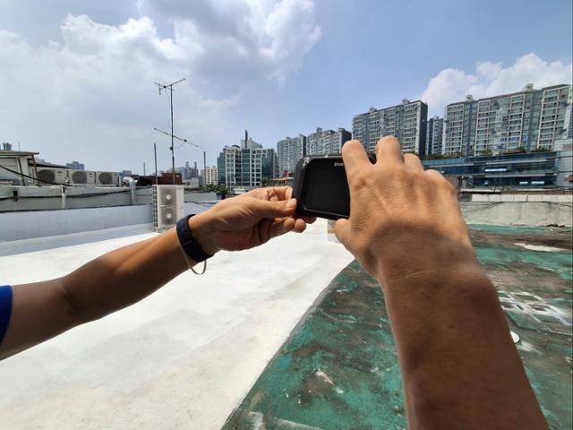 지난 8일 서울 영등포구 문래동의 3층 높이 상가 건물 옥상에서 조윤석 십년후연구소장이 열화상 카메라로 각각 흰색과 녹색으로 나뉘어진 옥상의 온도를 측정하고 있다. 홍인택 기자