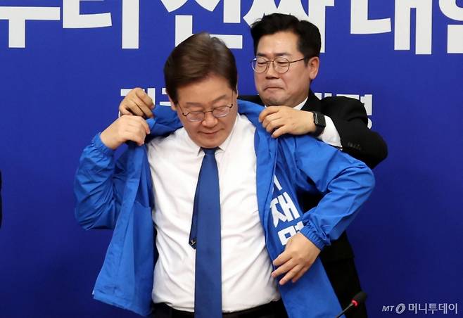 [서울=뉴시스] 조성봉 기자 = 박찬대 더불어민주당 대표 직무대행 겸 원내대표가 28일 오전 서울 여의도 국회에서 열린 최고위원회의에서 이재명 더불어민주당 제21대 대통령 선거 후보의 선거운동복을 입혀주고 있다. 2025.04.28. suncho21@newsis.com /사진=조성봉