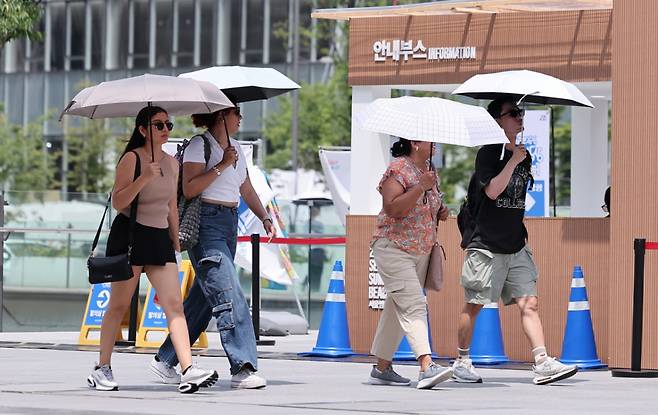 낮 최고기온이 35도까지 오르며 전국이 무더운 날씨를 보인 23일 서울 종로구 광화문광장에서 외국인 관광객들이 양산을 쓴 채 발걸음을 옮기고 있다./사진=뉴스1.