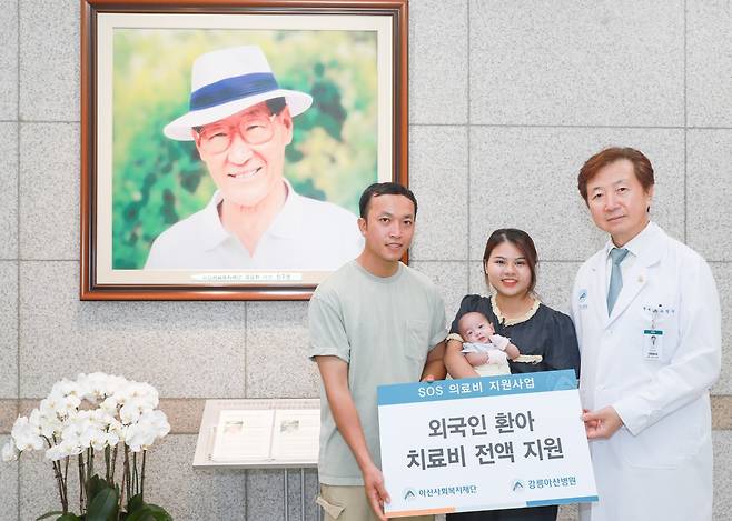 유창식 병원장과 환아의 가족이 고(故) 정주영 아산사회복지재단 설립자의 사진 앞에서 기념촬영을 하고 있다.[강릉아산병원 제공]