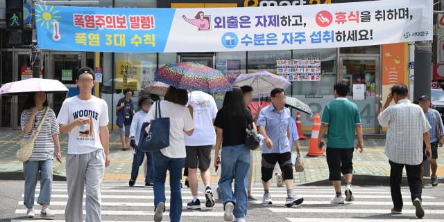 서울 전역에 폭염경보가 발령되는 등 가마솥더위가 이어진 24일 양산을 쓴 시민들이 서울 서대문구 거리에서 폭염시 행동 수칙이 담긴 현수막 앞을 지나고 있다. 금요일인 25일과 토요일인 26일에는 서울의 한낮 최고기온이 각각 37도와 38도까지 오를 것으로 보인다. 오승현 기자