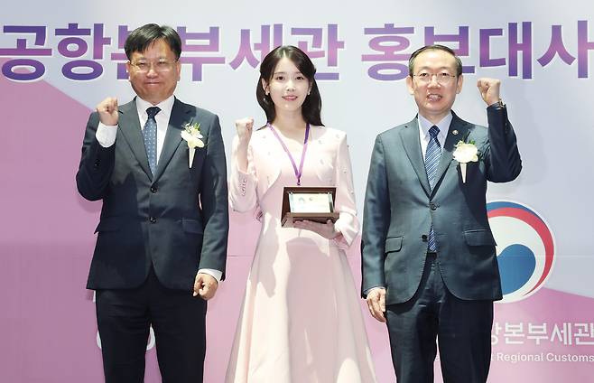 &nbsp;아이유가 25일 인천국제공항 제1여객터미널에서 열린 인천공항세관 홍보대사 위촉식에서 이명구 관세청장(오른쪽)과 김종호 인천공항본부세관장에게 홍보대사 위촉장·위촉패를 수여받은 뒤 기념촬영을 하고 있다. 연합뉴스
