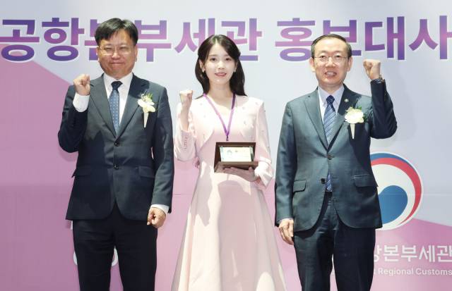 가수 아이유가 25일 인천국제공항 제1여객터미널에서 열린 인천공항세관 홍보대사 위촉식에서 이명구 관세청장(오른쪽)과 김종호 인천공항본부세관장에게 홍보대사 위촉장·위촉패를 수여받은 뒤 기념촬영을 하고 있다. 사진 제공=인천공항세관