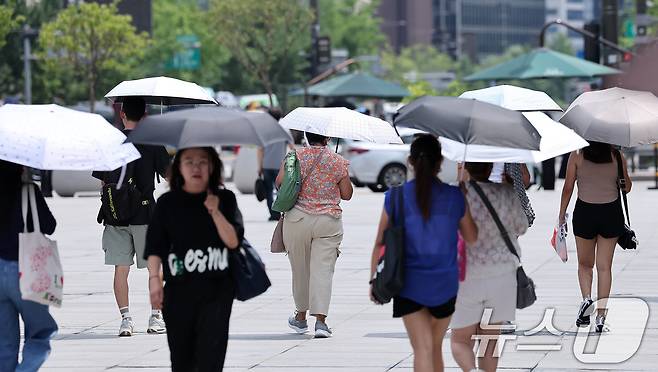 낮 최고기온이 35도까지 오르며 전국이 무더운 날씨를 보인 23일 서울 종로구 광화문광장에서 시민들이 양산을 쓴 채 발걸음을 옮기고 있다. 2025.7.23/뉴스1 ⓒ News1 김성진 기자