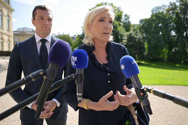 마린 르 펜 프랑스 극우 국민연합(RN) 지도자가 지난해 파리 엘리제궁에서 에마뉘엘 마크롱 대통령과 새 정부 구성에 관해 논의하고 나오며 기자들의 질문에 답하고 있다. 뒤편에는 국민연합 총리 후보인 조던 바르델라 대표이다./AP=뉴시스
