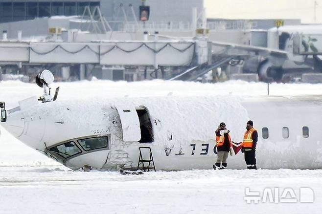 [토론토=AP/뉴시스] 18일(현지 시간) 캐나다 토론토 피어슨 공항 활주로에 전복 사고 델타항공 소속 항공기가 뒤집힌 채 놓여 있다. 지난 17일 발생한 델타항공 여객기 전복 사고에도 탑승객 80명 전원이 생존한 것은 철저한 안전설계와 구조대·승무원들의 신속한 대응 덕분인 것으로 알려졌다. 2025.02.19.