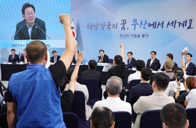 윤병철 대한민국공무원노동조합총연맹 해양수산부지부 위원장(왼쪽 파란 조끼)이 25일 부산 부경대에서 이재명 대통령이 참석한 가운데 열린 타운홀미팅 '부산의 마음을 듣다' 간담회에서 손을 들어 발언권을 요청하고 있다./연합뉴스/