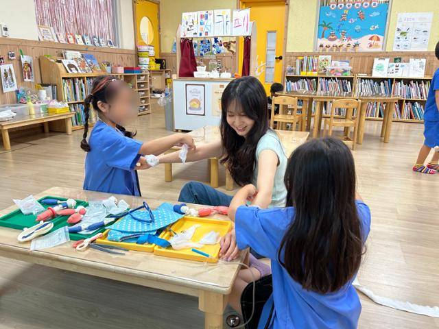 아이들이 노연경 교사의 팔에 종이를 붙이며 놀고 있다. 노 교사 제공