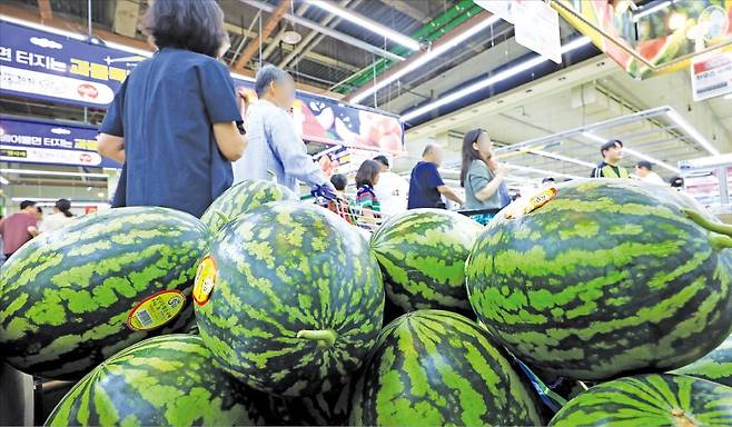 < 수박 한 통에 3만원 육박 > 폭우에 이어 폭염이 이어지면서 주요 농·수·축산물 가격이 치솟고 있다. 27일 서울의 한 대형마트를 찾은 소비자들이 수박 진열대 앞을 지나고 있다. 한국농수산식품유통공사 농산물유통정보에 따르면 수박 한 통 가격은 2만8809원으로 이달 들어 23% 급등했다.  뉴스1