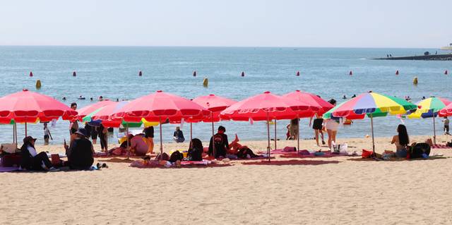 폭염이 이어진 25일 인천 중구 을왕리해수욕장을 찾은 피서객들이 파라솔 그늘에서 더위를 식히고 있다. 연합뉴스